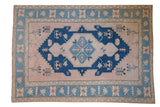 Vintage Distressed Oushak carpet with cobalt and powder blue medallion on dusty blush, 7' x 10'1