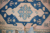 Cobalt blue, dusty blush, and ivory primitive floral medallion on distressed Oushak.