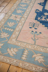 Distressed Oushak rug detail: dusty blush field, powder blue border with plant motifs.