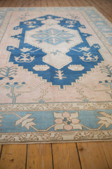 Distressed Oushak rug border showing powder blue and dusty blush germinating plants.