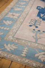 Distressed vintage Oushak carpet texture, showing powder blue border and ivory motifs.
