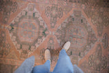 Distressed Soumac carpet showcasing geometric floral patterns in blush and charcoal.