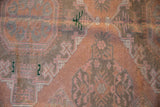 Detail of vintage Soumac carpet, distressed dusty blush and charcoal geometric patterns.