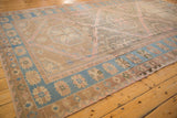 Distressed Caucasian Soumac rug detail: sky blue border, playful floral motifs, geometric pale coffee field.