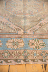 Distressed Soumac rug's border with reciprocating wave motif and sky blue, dusty rose hues.
