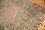 Distressed vintage Soumac rug with pale rose, blue, and brown geometric patterns.
