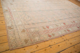 Distressed Oushak carpet corner with playful rose, tangerine, and red borders.