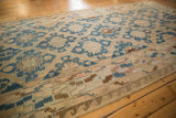Vintage distressed Soumac carpet showing indigo blue medallions and a bold wave border.