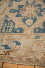 Reciprocating wave motif on the distressed Soumac rug's outer border in beige and blue.