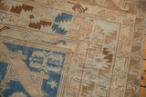 Distressed Soumac carpet corner, highlighting textured weave and geometric beige and blue borders.