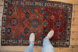 Fine Antique Malayer rug with madder red Harshang floral pattern, showing feet for scale.
