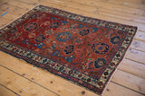 Antique Malayer rug corner: red Harshang field with sapphire blue florals, colorful boteh border.