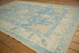 Distressed Oushak rug corner: soft powder blue, ivory vinery, and original selvage.