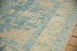 Soft distressed Oushak pile with powder blue field, ivory vinery, and original selvage.