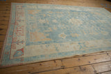 Corner detail of distressed Oushak rug showing ivory border, terracotta motifs, and secure selvage.