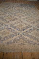 Distressed vintage Soumac carpet's geometric border and faded field patterns in beige and muted blue.