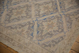 Distressed Soumac carpet's beige and blue geometric zigzag border and lattice field.