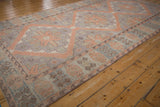 Vintage distressed Soumac rug corner with intact side cord selvage and geometric motifs in dusty blush and mauve.