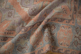 Textured close-up of vintage distressed Soumac carpet; dusty blush, mauve, powder blue geometric motifs.