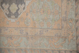 Distressed Soumac carpet: muted beige, slate minor medallions, floral guls, and wave motif.