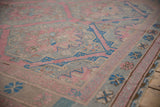 Distressed Soumac flatweave texture showing pink and sapphire blue hexagonal floral medallions from an angle.