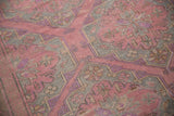 Textured weave of a vintage Soumac rug featuring floral medallions in pink, slate blue, and mauve.