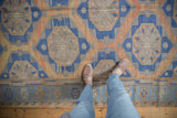 Distressed Soumac carpet with starburst medallions and abrashed lattice in terracotta and blue.