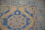 Vintage Soumac rug detail: geometric paneled medallions with starbursts in blue, dusty terracotta, and sand.