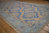 Soumac carpet corner with geometric border and starburst design in muted blue, beige, terracotta.