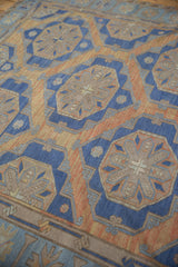 Distressed vintage Soumac carpet with blue and terracotta starburst medallions.
