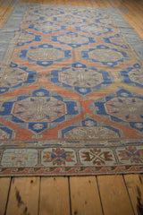 Distressed Soumac rug: geometric border, abrashed field, with terracotta, blue, and sand tones.