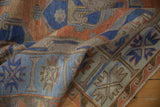 Distressed Soumac carpet corner detail in terracotta, sky blue, and sand geometric patterns.
