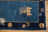Visible wear on the cobalt blue field of an antique Peking rug, showing the germinating plant motif.