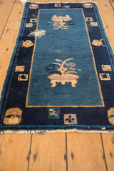 Detail of antique Peking rug's cobalt blue field, visible foundation wear, and fringe tatter.