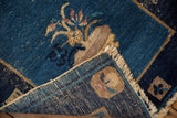 Antique Peking rug corner: cobalt blue pile, exposed foundation, and tattered fringe.
