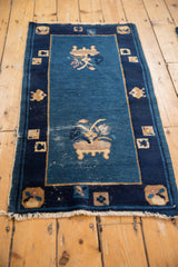 Corner of antique Peking runner, featuring dark blue border, pictorial cartouche, and visible pile wear.