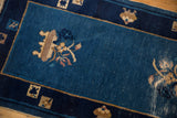 Antique Peking rug's cobalt blue field, beige germinating plant motif, and border cartouches.