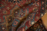 Distressed Mehrivan rug pile detail, featuring worn black cherry red, navy, and sky blue motifs.