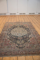 Distressed vintage Farahan Sarouk rug with scalloped medallion, curvilinear vinery, faded navy and blush.