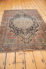 Distressed Farahan Sarouk rug corner showing curvilinear blossoms, dusty rose, and even wear.