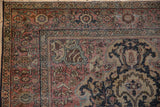 Distressed vintage Farahan Sarouk rug corner, with blush, navy, and ivory curvilinear floral motifs.