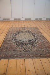 Distressed end of vintage Farahan Sarouk rug, featuring muted floral blossoms and delicate fringe.