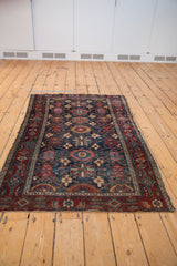 Malayer rug border with samovar, vinery, boteh, and time-softened navy, red, gold florals.