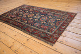 Vintage Malayer rug corner: red samovar border, vinery, and worn navy floral field.