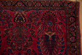 Vintage Sarouk rug corner with raspberry red field and indigo floral sprays.