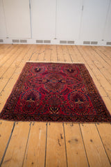 Corner of vintage American Sarouk rug, raspberry red field with indigo floral sprays.
