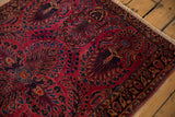 Vintage Sarouk rug corner with dense floral sprays, indigo border, and light fringe.