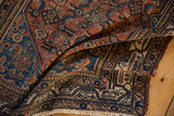 Hand knotted Malayer rug corner: madder red field, indigo borders, intricate pawn motif.