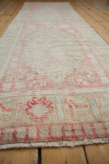 Distressed Oushak runner pile with faded blush floral patterns and ivory ground.