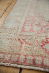 Textural detail of the vintage distressed Oushak runner, showing ivory pile and faded blush pink motifs.
